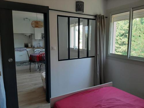 une chambre avec un lit rose et une cuisine dans l'établissement La Ciotat - T2 à 150m des plages avec parking privée, à La Ciotat