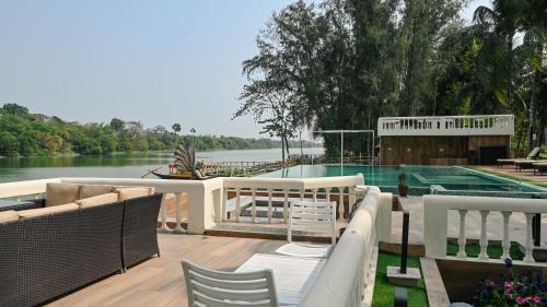 a deck with chairs and a swimming pool next to the water at Damodar River Retreat, Uluberia in Uluberiya