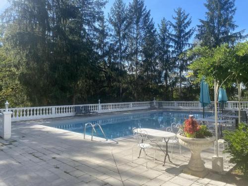 a swimming pool with a table and chairs next to a fence at Logis Vélès in Aubin