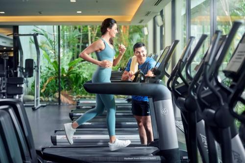 un hombre y una mujer corriendo en una cinta de correr en un gimnasio en Shangri-La Kuala Lumpur en Kuala Lumpur