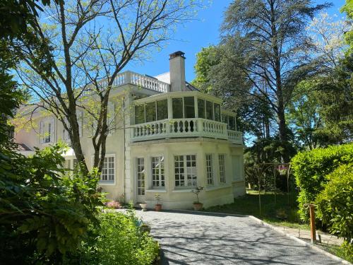 a large white house with a balcony on top at Logis Vélès in Aubin