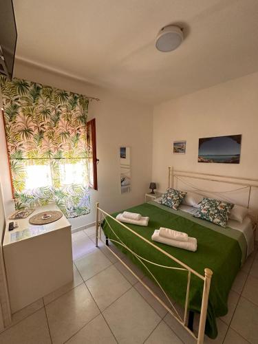 - une chambre avec un lit et une couverture verte dans l'établissement A Due Passi dal Centro, à Favignana