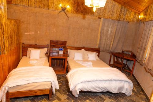 two beds in a room with two tables at Bagaicha Adventure Resort in Maruwā Ghāt