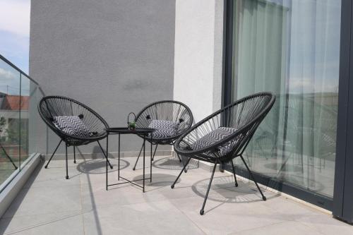 three chairs and a table on a balcony at Apartmani Royal Osijek in Osijek