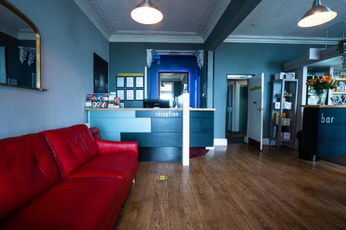 a living room with a red couch and a counter at The Central Hotel in Llandudno