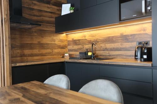 a kitchen with black cabinets and a wooden wall at Apartmani Royal Osijek in Osijek