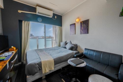 Habitación de hotel con cama y sofá en Hotel SERA LUNA -ホテル セラルナ- en Naha
