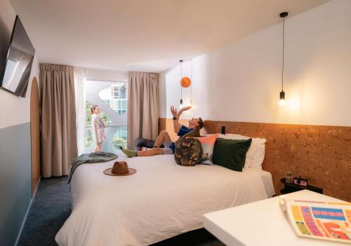 ブリスベンにあるLyLo Brisbaneのホテルの部屋のベッドに横たわる女性