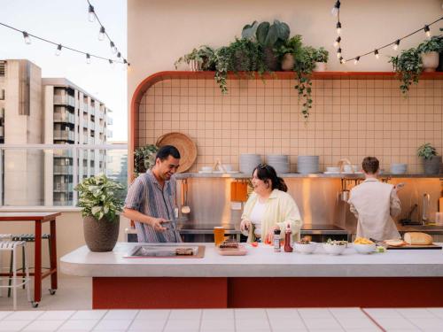 a man and woman preparing food in a kitchen at LyLo Brisbane in Brisbane