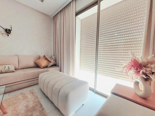 un salon avec un canapé et une fenêtre avec des stores dans l'établissement Très bel appart climatisé proche de la plage, à Agadir