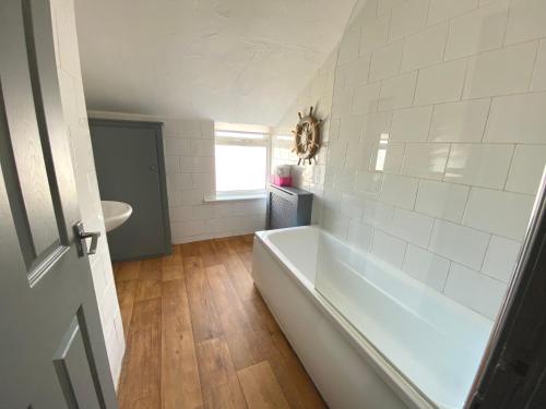 a white bathroom with a tub and a sink at Simpson Beach View Apartments by Blackpool Service Apartments in Blackpool