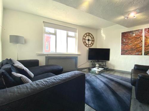 a living room with a couch and a tv at Simpson Beach View Apartments by Blackpool Service Apartments in Blackpool