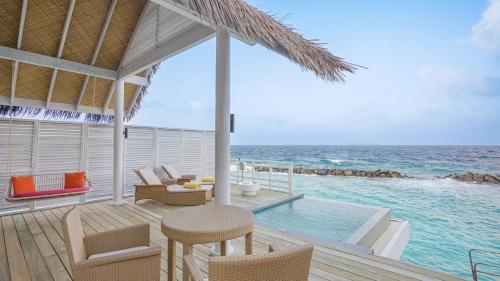a villa with a pool and a deck with a table and chairs at Amaya Kuda Rah in Dhangethi
