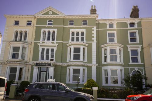 a green building with a car parked in front of it at The Central Hotel in Llandudno
