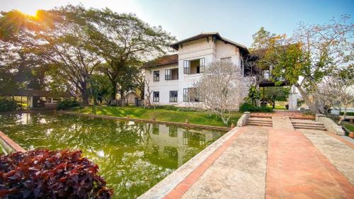 a house with a pond in front of it at The Grand Luang Prabang, Affiliated by Meliá in Luang Prabang