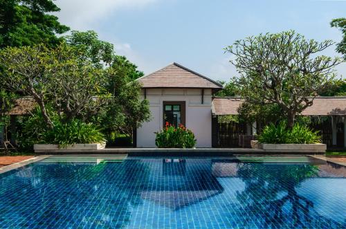 a swimming pool in front of a house with trees at The Grand Luang Prabang, Affiliated by Meliá in Luang Prabang
