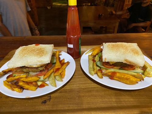two plates of food with a sandwich and french fries at Dira Bungalows in Tetebatu