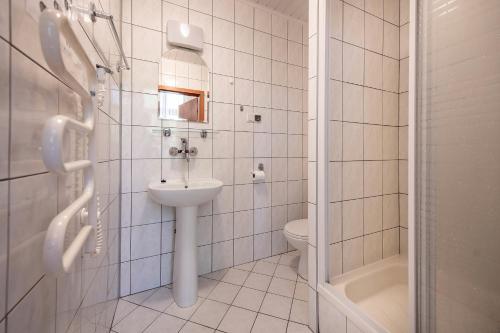 a white tiled bathroom with a sink and a toilet at FWP Rybniczanka - Wanda in Lądek-Zdrój