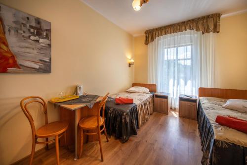 Cette chambre comprend deux lits, une table et des chaises. dans l'établissement FWP Rybniczanka - Wanda, à Lądek-Zdrój