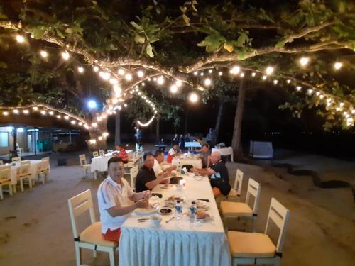 een groep mensen die aan een tafel zitten te eten bij New Belitung Holiday Resort in Pasarbaru