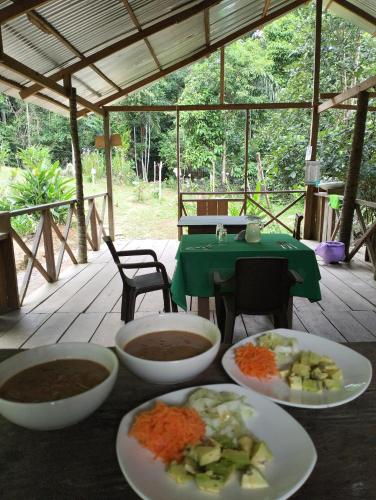 a table with bowls of soup and plates of food at Cabañas eco lógicas mu'ü in Loreto Mocagua