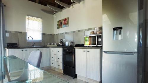 a kitchen with white cabinets and a black appliance at The Owls Inn Country Villa's in George