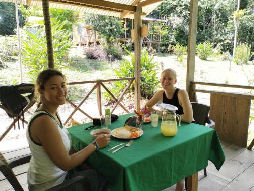 two women sitting at a table with a green table cloth at Cabañas eco lógicas mu'ü in Loreto Mocagua