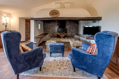a living room with blue chairs and a fireplace at Villanovia Country House in Volterra