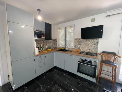 une cuisine avec des armoires blanches et un four à plaques de cuisson dans l'établissement maison familiale eaubonne, à Eaubonne