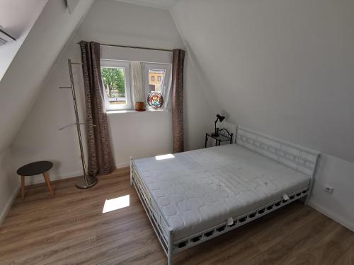 a white bedroom with a bed and a window at Im Herzen des Kraichgaus 2 in Östringen