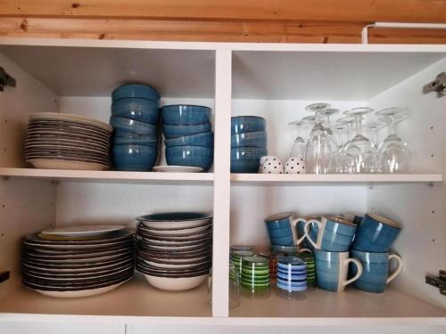 a shelf with blue plates and bowls and glasses at Chalet Blockhaus auf Camping - b48513 in Oberwil