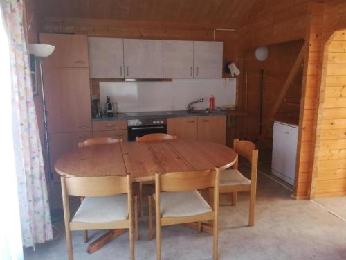 uma cozinha com uma mesa de madeira e algumas cadeiras em Chalet Blockhaus auf Camping - b48513 em Oberwil