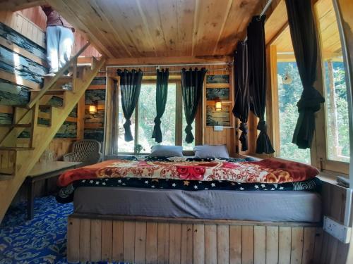 a bedroom in a tree house with a bed at Stone Cottage and Tree House by StayApart in Jibhi