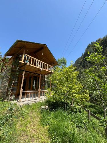 a wooden house on a hill with trees at Stone Cottage and Tree House by StayApart in Jibhi