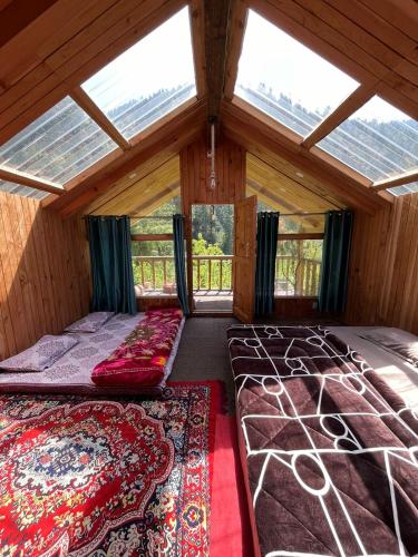 a large room with two beds and a window at Stone Cottage and Tree House by StayApart in Jibhi