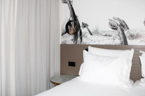 een slaapkamer met een bed met witte lakens en een raam bij AP Cabanas Beach & Nature - Adults Friendly in Cabanas de Tavira