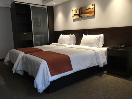 a bedroom with a large bed with white and brown sheets at Crystal Tower in Montevideo