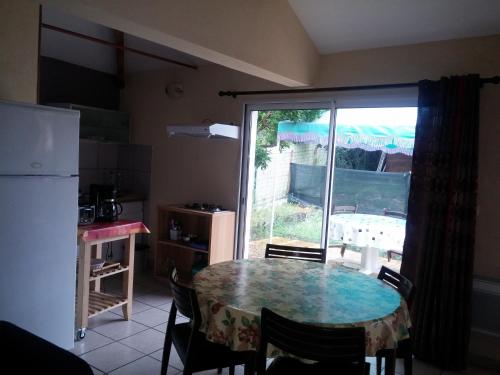 une cuisine avec une table avec des chaises et un réfrigérateur dans l'établissement T1 47m2 + Jardin 60m2, à La Teste-de-Buch