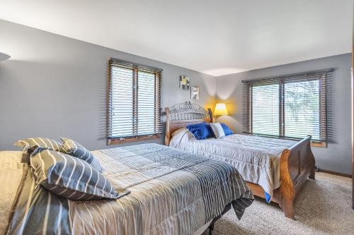 a bedroom with two beds and two windows at Serene Riverside Retreat home in Little Suamico