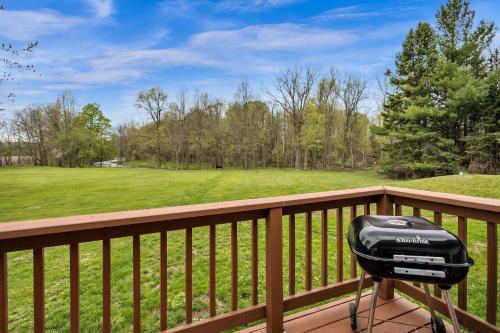 a grill on a wooden balcony with a field at Serene Riverside Retreat home in Little Suamico