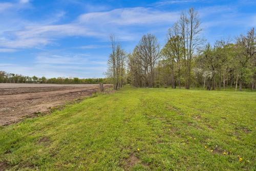 an empty field with trees in the background at Serene Riverside Retreat home in Little Suamico