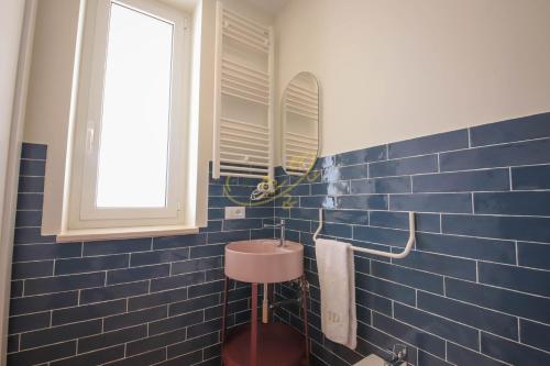 a blue tiled bathroom with a sink and a mirror at Alberobbè luxury rooms in Alberobello
