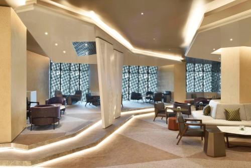 a lobby with chairs and tables and windows at Hilton Bahrain in Manama