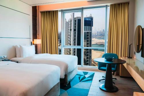 Hilton Bahrain في المنامة: غرفة فندقية بسريرين ونافذة كبيرة