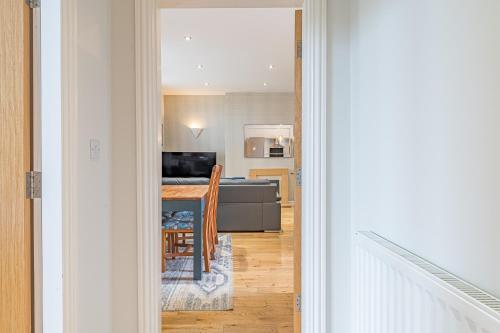 a hallway leading to a kitchen with a table and a living room at Abbey Apartments Modern ApartHotel for Tourists & Professionals in Barrow in Furness