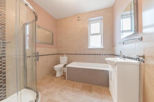 a bathroom with a tub and a sink and a toilet at Abbey Apartments Modern ApartHotel for Tourists & Professionals in Barrow in Furness