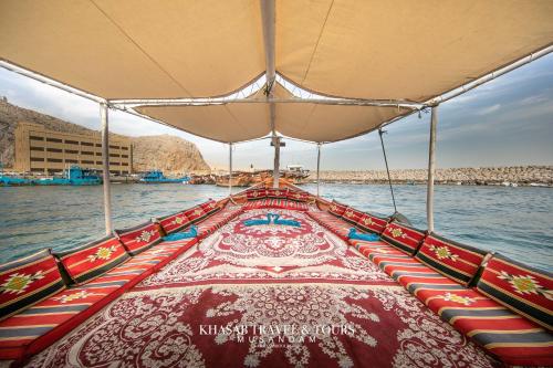 um barco com assentos coloridos na água em Overnight Dhow - 1 Night 2 Days em Khasab