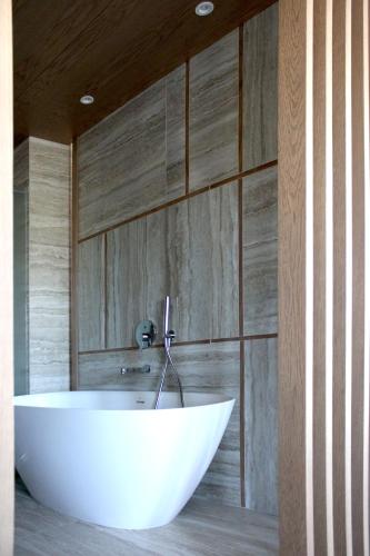 a white tub in a bathroom with wooden walls at AP Cabanas Beach & Nature - Adults Friendly in Cabanas de Tavira