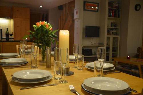 a wooden table with plates and glasses and a candle at Au Pied des Pistes C7, Grimentz - Modern 3 Bedroom Duplex, Sleeps 8 in Grimentz