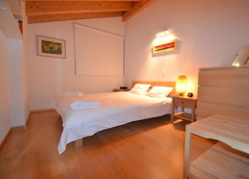 a bedroom with a white bed and a wooden floor at Au Pied des Pistes C7, Grimentz - Modern 3 Bedroom Duplex, Sleeps 8 in Grimentz